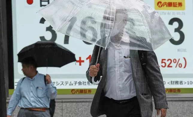 A person walks in front of an electronic stock board showing Japan's Nikkei index at a securities firm Tuesday, June 3, 2025, in Tokyo. (AP Photo/Eugene Hoshiko)