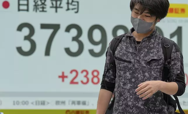 A person walks in front of an electronic stock board showing Japan's Nikkei index at a securities firm Monday, May 26, 2025, in Tokyo. (AP Photo/Eugene Hoshiko)