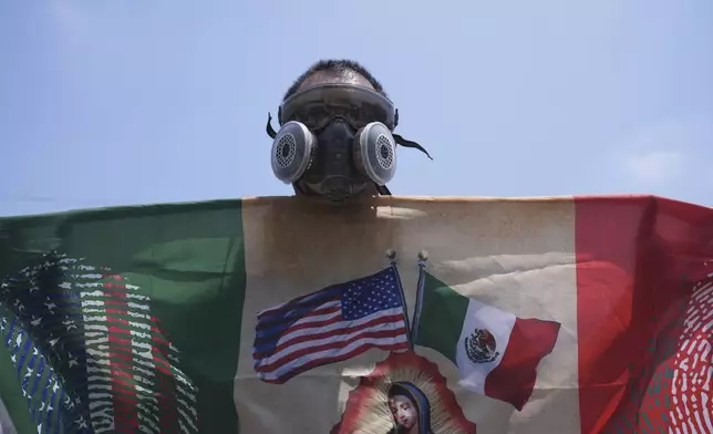 A protester wears a respirator outide a detention center in downtown Los Angeles, Sunday, June 8, 2025, following last night's immigration raid protest. (AP Photo/Jae Hong)
