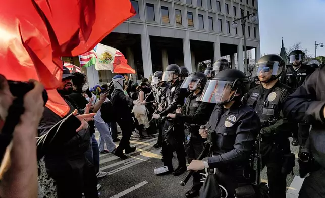 Los Angeles police in riot gear form a skirmish line and push back protesters down a street away from a federal building in downtown Los Angeles on Monday, June 9, 2025. (AP Photo Jae Hong)