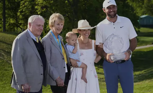 Scottie Scheffler, right, holds the trophy as he poses for a photo with his wife Meredith, second from right, and son Bennett, center, and Jack, left, and Barbara Nicklaus, second from left, after winning the Memorial golf tournament Sunday, June 1, 2025, in Dublin, Ohio. (AP Photo/Sue Ogrocki)