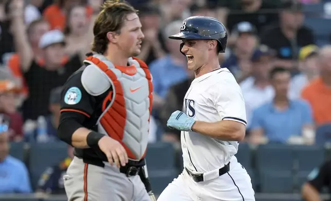 Tampa Bay Rays' Jake Mangum, right, reacts as he scores behind Baltimore Orioles catcher Adley Rutschman on a bunt single by Christopher Morel during the second inning of a baseball game Monday, June 16, 2025, in Tampa, Fla. (AP Photo/Chris O'Meara)