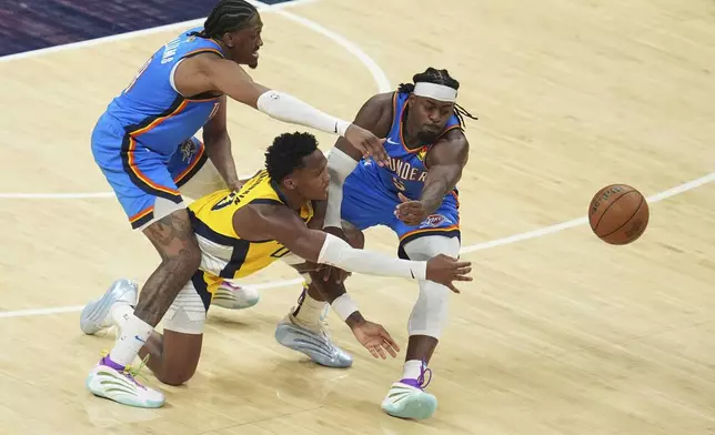 Indiana Pacers guard Bennedict Mathurin passes the ball under pressure from Oklahoma City Thunder forward Jalen Williams, right, during the second half of Game 3 of the NBA Finals basketball series, Wednesday, June 11, 2025, in Indianapolis. (AP Photo/Michael Conroy)