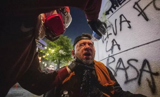 An injured protester is tended to by another during protests over the Trump administration's immigration raids in Los Angeles, Monday, June 9, 2025. (AP Photo/Ethan Swope)