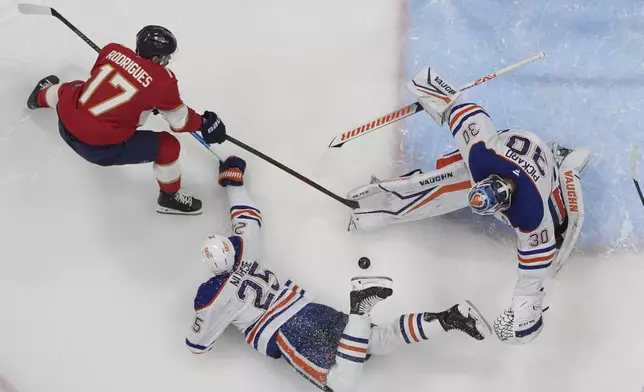 Florida Panthers right wing Mackie Samoskevich (25) defends Florida Panthers center Evan Rodrigues (17) as goaltender Calvin Pickard (30) deflects a shot on goal during the third period of Game 4 of the NHL hockey Stanley Cup Final Friday, June 13, 2025, in Sunrise, Fla. (AP Photo/Lynne Sladky)