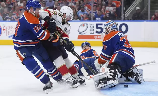 Florida Panthers' Brad Marchand (63) scores against Edmonton Oilers goalie Calvin Pickard (30) as OIlers' Corey Perry (90) defends and Oilers' Jake Walman, second from left, watches during the third period in Game 5 of the NHL hockey Stanley Cup Final in Edmonton, Alberta, Saturday, June 14, 2025. (Darryl Dyck/The Canadian Press via AP)
