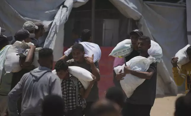 Palestinians carry bags containing food and humanitarian aid packages delivered by the Gaza Humanitarian Foundation, a U.S.-backed organization, in Rafah, southern Gaza Strip, Sunday, June 8, 2025. (AP Photo/Abdel Kareem Hana)