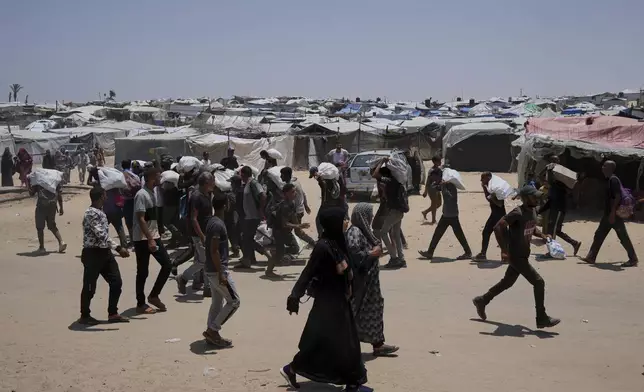 Palestinians carry bags containing food and humanitarian aid packages delivered by the Gaza Humanitarian Foundation, a U.S.-backed organization, in Rafah, southern Gaza Strip, Sunday, June 8, 2025. (AP Photo/Abdel Kareem Hana)