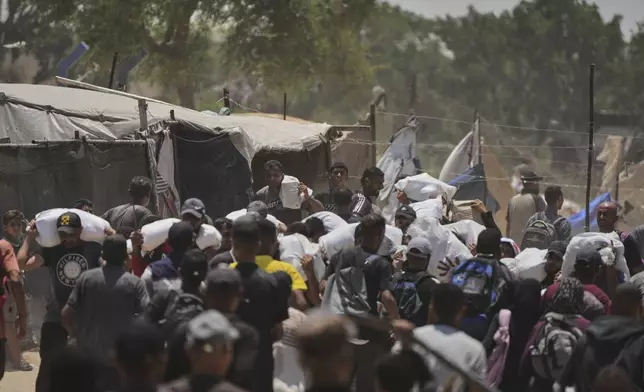 Palestinians carry bags containing food and humanitarian aid packages delivered by the Gaza Humanitarian Foundation, a U.S.-backed organization, in Rafah, southern Gaza Strip, Sunday, June 8, 2025. (AP Photo/Abdel Kareem Hana)