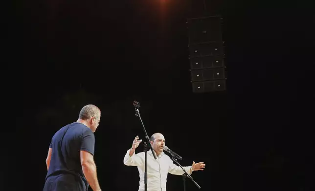 Cypriot lyricists Savvas Demetriou, 46, right, and Constantinos Christou Girlias, 44, battle it out live on stage in the centuries-old duel known as "tsiattista" at the Pentecost Festival in Cyprus' southern coastal town of Larnaca, Sunday, June 8, 2025. (AP Photo/Petros Karadjias)