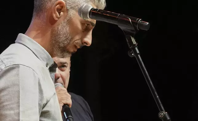 Cypriot lyricists Savvas Demetriou, 46, right, and Elias Hadjimihael, 38, battle it out live on stage in the centuries-old duels known as "tsiattista" at the Pentecost Festival in Cyprus' southern coastal town of Larnaca, Sunday, June 8, 2025. (AP Photo/Petros Karadjias)