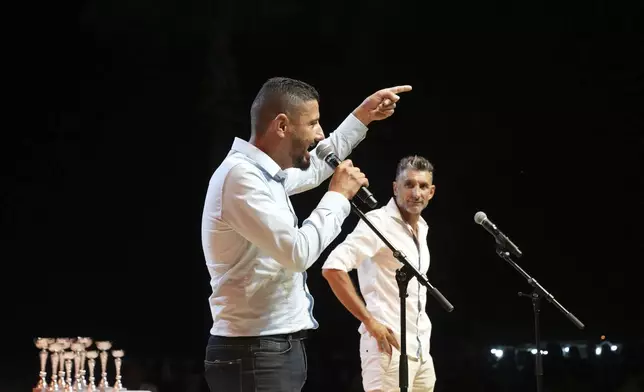 Cypriot lyricists Adamos Peratikos, 41, left, and Antonis Papaioannou, 43, battle it out live on stage in the centuries-old duel known as "tsiattista" at the Pentecost Festival in Cyprus' southern coastal town of Larnaca, Sunday, June 8, 2025. (AP Photo/Petros Karadjias)