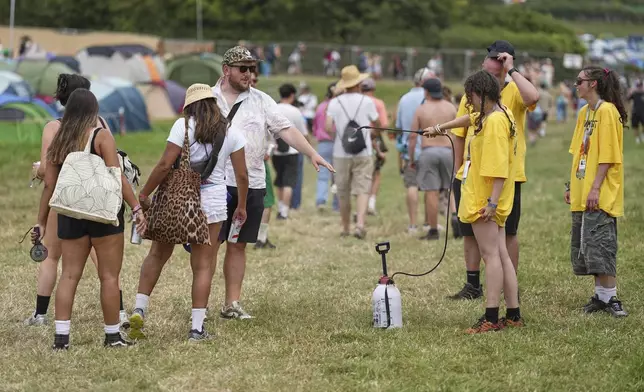 Festival goers are sprayed with water to cool down in the heat during the Glastonbury Festival in Worthy Farm, Somerset, England, Wednesday, June 25, 2025. (Scott A Garfitt/Invision/AP)
