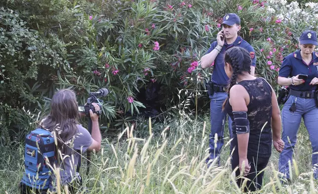 A woman films as a passerby stops by forensic police working at the site of the discovery of the body of an infant and the infant’s mother, in Rome’s Villa Pamphili park, Saturday, June 7, 2025. (Francesco Benvenuti/LaPresse via AP)