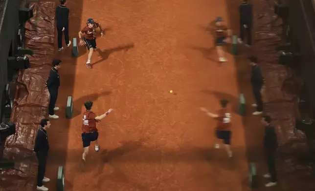 Boy balls are reflected in a glass as they collect the ball during their semifinal match of the French Tennis Open between France's Lois Boisson and Coco Gauff of the U.S. at the Roland-Garros stadium in Paris, Thursday, June 5, 2025. (AP Photo/Thibault Camus)