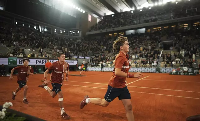 Ball boys run during a break at the semifinal match of the French Tennis Open between Aryna Sabalenka of Belarus and Poland's Iga Swiatek at the Roland-Garros stadium in Paris, Thursday, June 5, 2025. (AP Photo/Thibault Camus)