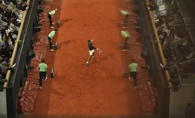Referees reflect in a glass as Italy's Lorenzo Musetti plays a shot against Spain's Carlos Alcaraz during their semifinal match of the French Tennis Open at the Roland-Garros stadium in Paris, Friday, June 6, 2025. (AP Photo/Aurelien Morissard)