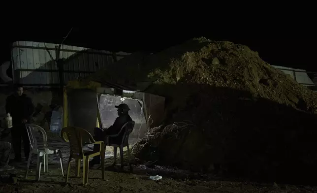 The Gaboa family, Bedouins living in Al-Furaa village in southern Israel, gather around the makeshift bomb shelter they made from two gravel trucks buried in dirt to protect them from incoming Iranian fire, Tuesday, June 17, 2025. (AP Photo/Maya Alleruzzo)