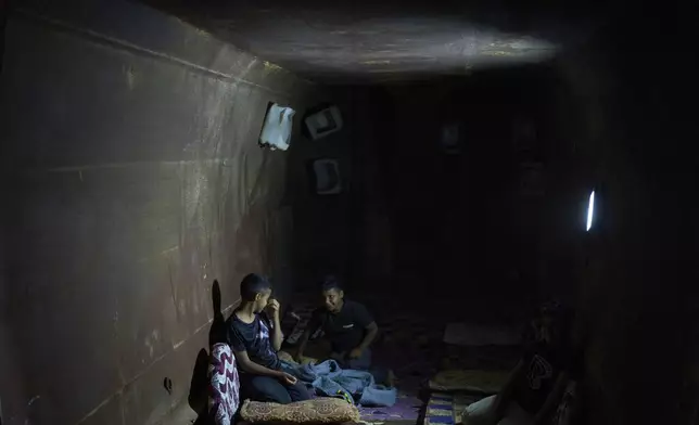 Boys from the Gaboa family, Bedouins living in Al-Furaa village in southern Israel, sit inside the makeshift bomb shelter made from two gravel trucks buried in dirt to protect them from incoming Iranian fire, Tuesday, June 17, 2025. (AP Photo/Maya Alleruzzo)