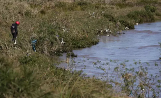 A police rescue officer searches for missing people of this week's floods in Mthatha, South Africa, Friday, June 13, 2025. (AP Photo/Themba Hadebe)