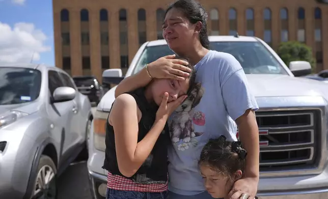 Narel Lopez comforts her daughters after her husband and a son were detained and taken away in a bus following an appearance at immigration court, Wednesday, June 25, 2025, in San Antonio, Texas. (AP Photo/Eric Gay)