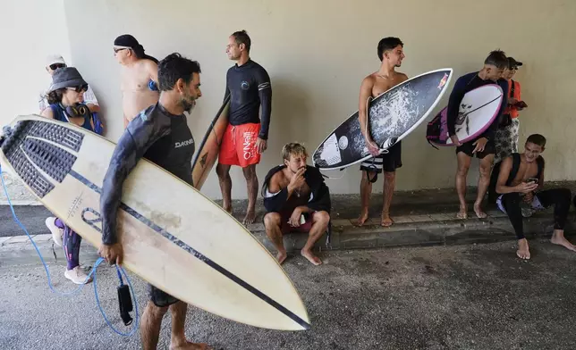 Surfers take shelter as air raid sirens warn of incoming Iranian strikes in Haifa beachfront, Israel, Tuesday, June 24, 2025, shortly after Israel and Iran accepted a ceasefire plan proposed by President Donald Trump. (AP Photo/Baz Ratner)