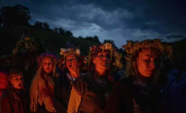 People wear traditional Lithuanian village-styled clothes as they celebrate Saint John's Day and the summer solstice in the small town of Kernave, some 35km (22 miles) northwest of the capital, Vilnius, Lithuania, Monday, June 23, 2025. (AP Photo/Mindaugas Kulbis)