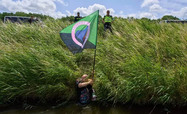 Police repel demonstrators with Extinction Rebellion who crossed a moat in an attempt to block the A44 motorway, closed off to all traffic except for arriving and departing world leaders, in Abbenes, Netherlands, Monday, June 23, 2025, for the NATO summit in The Hague. (AP Photo/Peter Dejong)