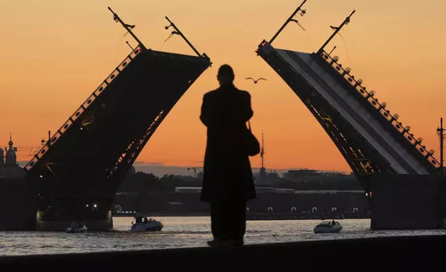 A man looks at the rising Dvortsovy (Palace) drawbridge on the Neva River in St. Petersburg, Russia, early Monday, June 23, 2025. (AP Photo/Dmitri Lovetsky)
