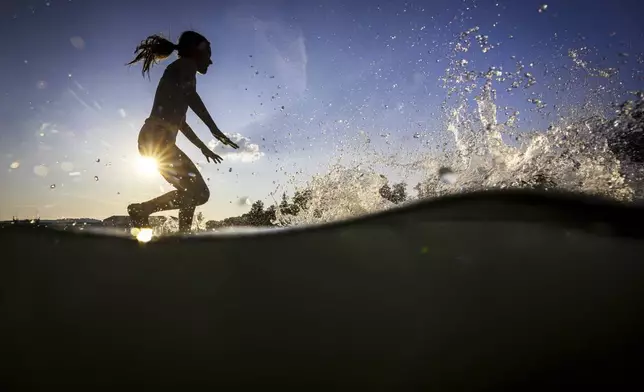 A girl jumps into the river Rhine to cool off during high temperatures, near Kaiserstuhl, Switzerland, Sunday, June 22, 2025. (Michael Buholzer/Keystone via AP)