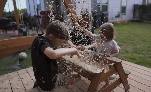 Eileen Lamb, center, who was diagnosed with autism as an adult, works with her son Charlie Lamb, left, who also has autism, and daughter Billie at their home, Monday, May 12, 2025, in Austin, Texas. (AP Photo/Eric Gay)
