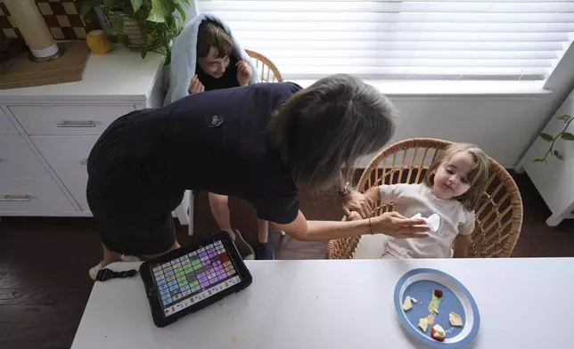 Eileen Lamb, who was diagnosed with autism as an adult, left, works with her son Charlie Lamb, top, who also has autism, and daughter Billie, at heir home, Monday, May 12, 2025, in Austin, Texas. (AP Photo/Eric Gay)