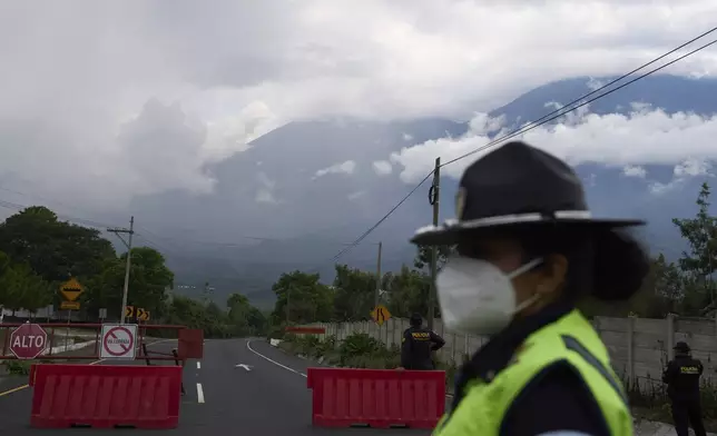 Police stand at a barricade near the Fuego Volcano in San Juan Alotenango, Guatemala, Thursday, June 5, 2025, after the volcano's explosive activity increased. (AP Photo/Moises Castillo)