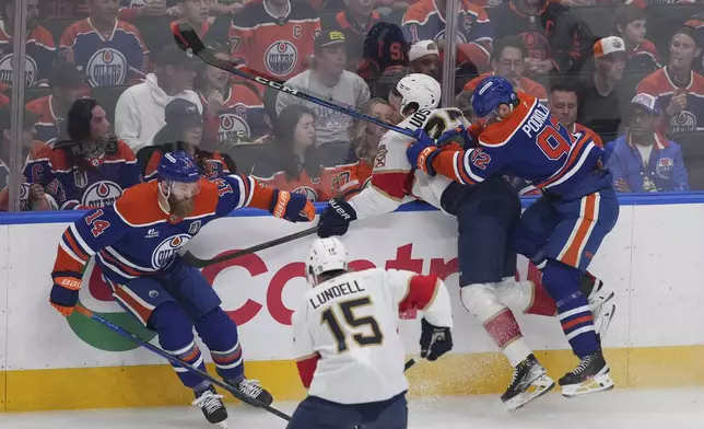 Edmonton Oilers' Vasily Podkolzin (92) checks Florida Panthers' Eetu Luostarinen during the first period in Game 1 of the NHL hockey Stanley Cup final series in Edmonton, Alberta, Wednesday, June 4, 2025. (Darryl Dyck/The Canadian Press via AP)