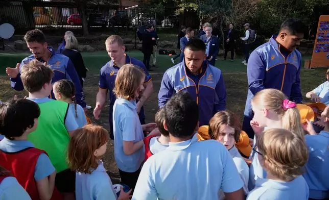 Australian rugby union players Jake Gordon, left, Max Jorgensen, second left, Allan Alaalatoa, and Will Skelton, right, interact with students at Stanmore Public School in Sydney, Australia, Thursday, June 19, 2025, after the announcement of the squad that will that will be considered for a position in the three-test series against the British and Irish Lions. (AP Photo/Rick Rycroft)