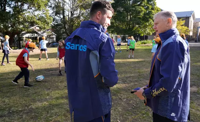 Australia Rugby head coach Joe Schmidt, right, talks with player Jake Gordon as students go through skill drills at Stanmore Public School in Sydney, Australia, Thursday, June 19, 2025, after the announcement of the squad that will that will be considered for a position in the three-test series against the British and Irish Lions. (AP Photo/Rick Rycroft)