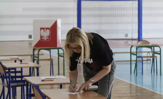 A woman prepares to cast her vote during the presidential election runoff in Warsaw, Poland, Sunday, June 1, 2025. (AP Photo/Czarek Sokolowski)