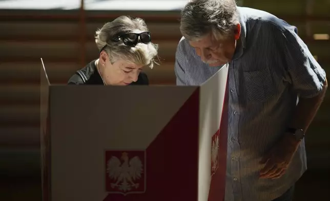 People prepare to vote during the presidential election runoff in Warsaw, Poland, Sunday, June 1, 2025. (AP Photo/Petr David Josek)