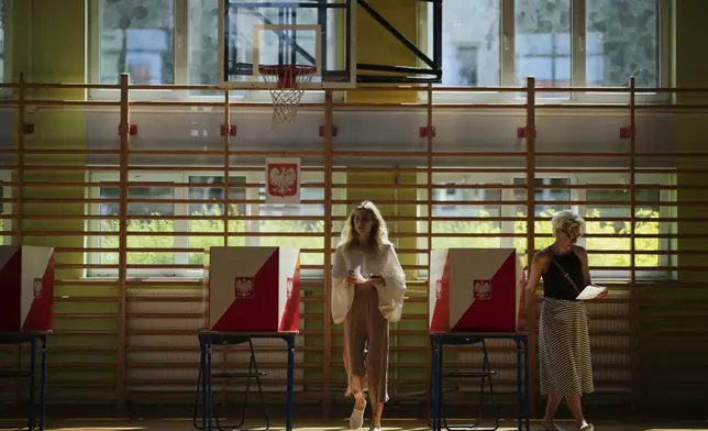A women prepares to cast her vote during the presidential election runoff in Warsaw, Poland, Sunday, June 1, 2025. (AP Photo/Petr David Josek)