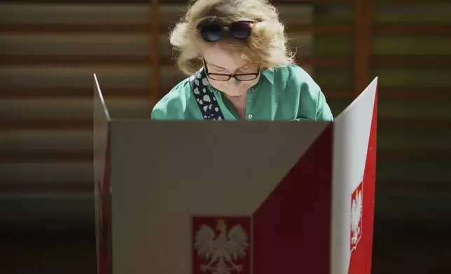 A woman prepares to cast her vote during the presidential election runoff in Warsaw, Poland, Sunday, June 1, 2025. (AP Photo/Petr David Josek)