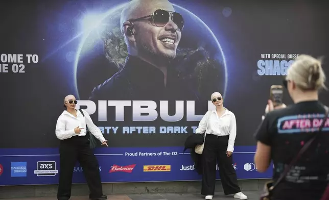 Fans pose for a photograph as they gather prior to a performance by Pitbull on Monday, June 9, 2025, in London. (Photo by Scott A Garfitt/Invision/AP)
