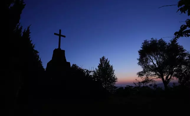 A Christian cross at a memorial park for Catholics martyred in the early 1600s is silhouetted before sunrise at Hirado, southern Japan, Tuesday, April 29, 2025. (AP Photo/Hiro Komae)