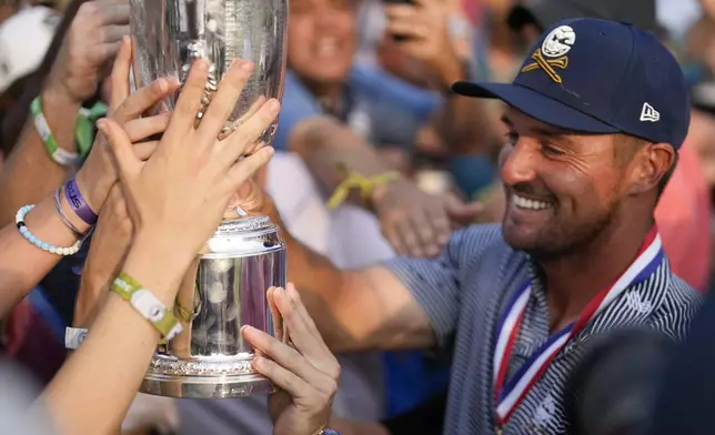 FILE - Bryson DeChambeau shows the trophy to fans after winning the U.S. Open golf tournament Sunday, June 16, 2024, in Pinehurst, N.C. (AP Photo/George Walker IV, File)