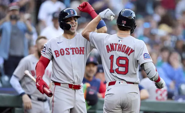 Boston Red Sox's Roman Anthony (19) is greeted by Marcelo Mayer, left, after hitting a solo home run off Seattle Mariners starting pitcher Logan Gilbert during the first inning of a baseball game Monday, June 16, 2025, in Seattle. (AP Photo/John Froschauer)