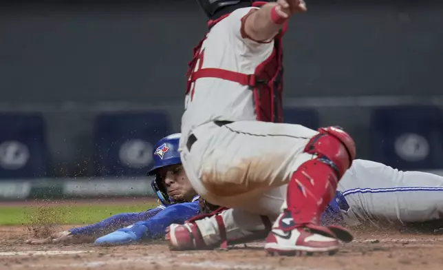 Toronto Blue Jays' Andres Gimenez, rear, is tagged out at home by Cleveland Guardians catcher Austin Hedges in the eighth inning of a baseball game in Cleveland, Tuesday, June 24, 2025. (AP Photo/Sue Ogrocki)