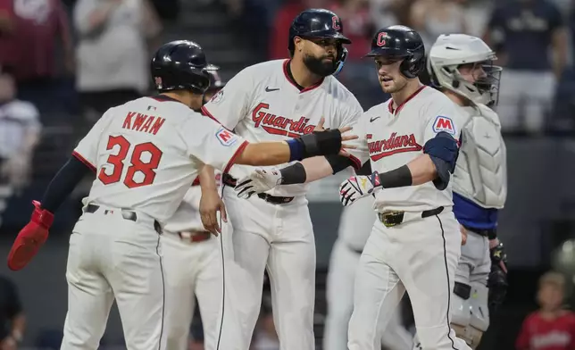 Cleveland Guardians' Lane Thomas, right, is greeted by Steven Kwan (38) and Johnathan Rodriguez, center, in front of Toronto Blue Jays catcher Alejandro Kirk after hitting a home run in the seventh inning of a baseball game in Cleveland, Tuesday, June 24, 2025. (AP Photo/Sue Ogrocki)