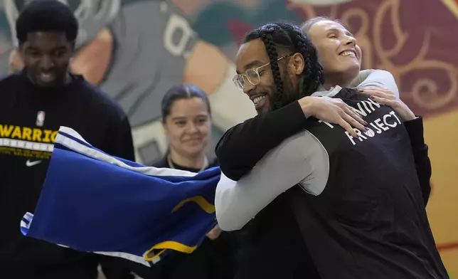 Haley Cremen, Program Coordinator of the Golden State Warriors Basketball Academy, right, hugs Jay Cornish as he and other Twinning Project cohort 2 participants graduate during the project's collaboration with the NBA's Golden State Warriors and the California Department of Corrections and Rehabilitation at Solano State Prison in Vacaville, Calif., Tuesday, Feb. 11, 2025. (AP Photo/Jeff Chiu)
