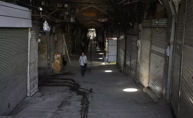 Few pedestrians walk along the historic Grand Bazaar as most shops remain shuttered, in Tehran, Iran, Monday, June 16, 2025. (AP Photo/Vahid Salemi)