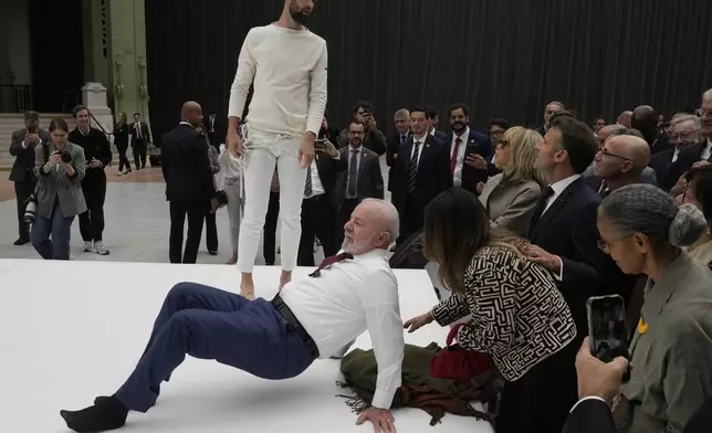 Brazil's President Luiz Inacio Lula da Silva tries to replicate a move by acrobats as part of a visit to an exhibition by Ernesto Neto Friday, June 6, 2025 at the Grand Palais museum in Paris. (AP Photo/Michel Euler, Pool)