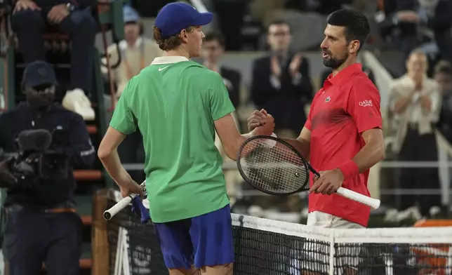 Winner Italy's Jannik Sinner, centre, and Serbia's Novak Djokovic shake hands after their semifinal match of the French Tennis Open at the Roland-Garros stadium in Paris, Friday, June 6, 2025.. (AP Photo/Thibault Camus)